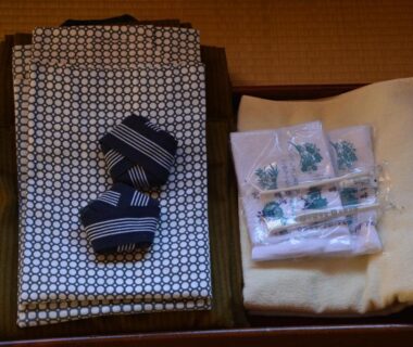 Folded patterned yukata, sandals, towel and wrapped toiletries arranged on tatami at Komaya Ryokan, Yamanashi