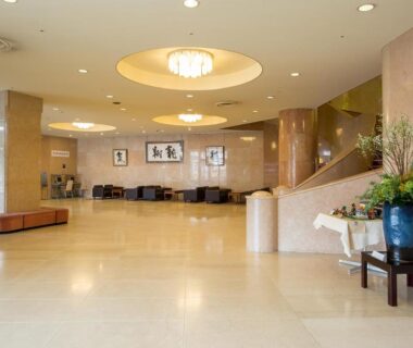 Open lobby with chandeliers, seating area and staircase at Komoro Grand Castle Hotel, Nagano