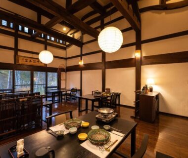 Interior dining space with tatami mats, low tables, wooden beams and paper lanterns at Konashi No Yu Sasaya, Nagano