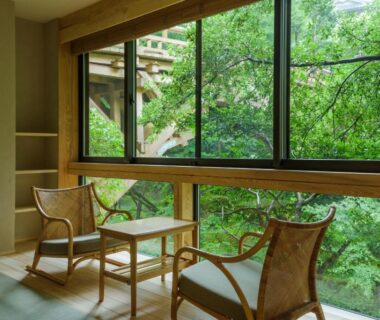 Tatami room seating with two woven chairs and low table facing a large window overlooking green foliage