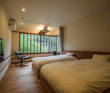 Two single beds, wooden floor and lounge chairs by large window at Koorogirou, Chūbu, Ishikawa, Japan
