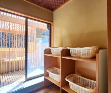 Wooden shelving with woven bathing baskets and sliding door to small veranda at Kose Onsen, Nagano