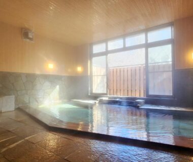 Sunlit indoor onsen with stone flooring and wooden ceiling at Kose Onsen in Nagano, Chūbu region, Japan