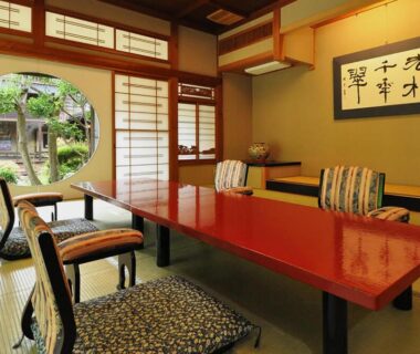 Traditional tatami room with low lacquer table and round garden window at Koshi no yado Takashimaya, Niigata