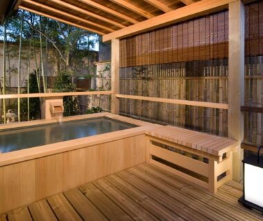 Wooden soaking tub on covered deck with bamboo screens and lantern at Koshi no yado Takashimaya Niigata