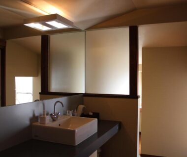 Sink and mirror with shoji screens and warm lighting in Kotsubokaigan Linca bathroom, Kanagawa