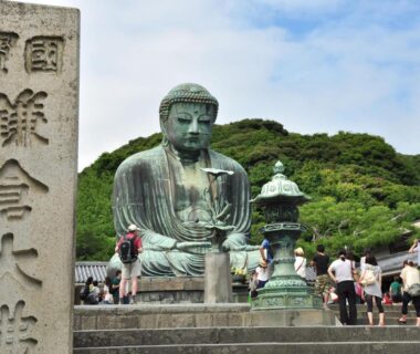 Outdoor bronze Buddha statue with visitors, near Kotsubokaigan Linca in Kanagawa