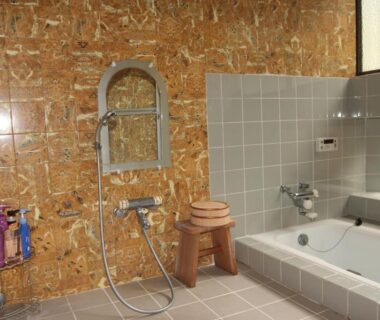 Indoor tiled bathing area with tub, shower, wooden stool and toiletries at Kougetsu Sanso in Tokyo