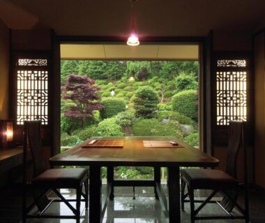 Low dining table and chairs framed by shoji screens overlooking landscaped garden at Kounkaku in Fukushima