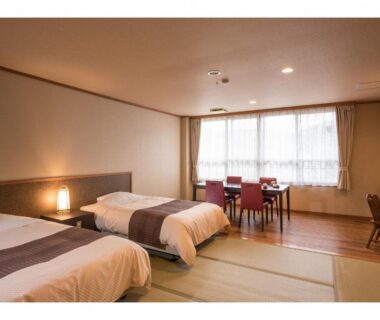 Spacious tatami room with twin beds, dining table and large window at Kouunsou in Kantō, Tochigi