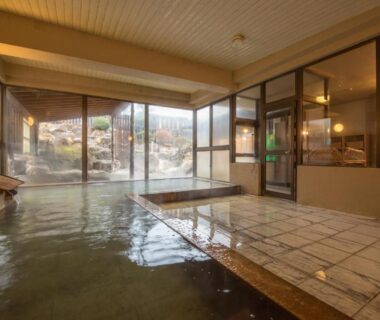 Indoor onsen bath with timber accents and floor-to-ceiling windows overlooking garden at Kouunsou, Tochigi, Kantō, Japan
