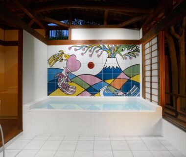 Tiled indoor onsen bath with colorful mountain mural, wooden beams and shoji screens at Kouyurou Ikawa in Shizuoka