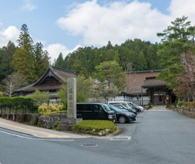 Entrance and parking area of Koyasan Sanadabo Rengejoin with traditional buildings and forested hillside in Wakayama
