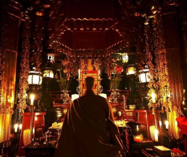 Monk seated before ornate Buddhist altar at Koyasan Shukubo Saizenin interior shrine in Wakayama temple lodging