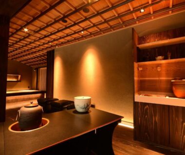 Warm-lit interior with low wooden counter, tea utensils, and shelving at Koyasan Shukubo Yochiin in Wakayama