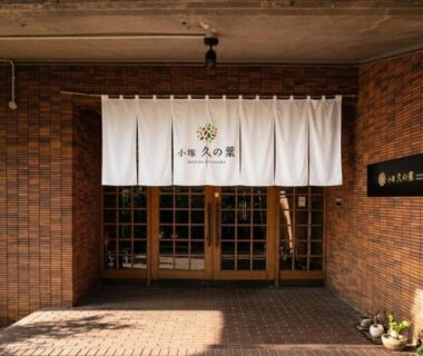White noren over wooden sliding doors at Kozuka Hisanoha entrance, brick facade, Kanagawa, Kantō, Japan
