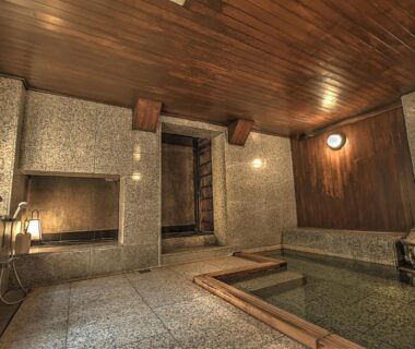 Indoor stone bathing area with wooden ceiling at K's House Ito Onsen in Shizuoka, Chūbu