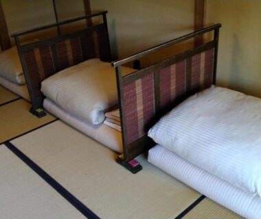Tatami floor room with folded futon bedding and low wooden headboards