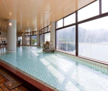 Tiled indoor onsen bath with large windows overlooking a lakeside view at Kumano-bettei Nakanoshima, Wakayama