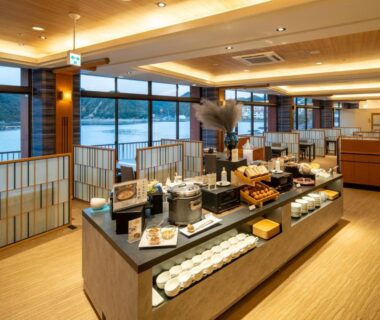 Buffet breakfast area with floor-to-ceiling windows overlooking water, wooden interior at Kumano-bettei Nakanoshima Wakayama