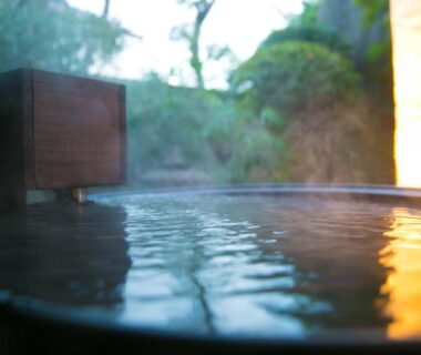 Steaming onsen bath with wooden edge at Kunisakisou overlooking garden in Ōita, Kyūshū, Japan