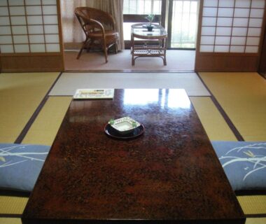 Traditional tatami room with low lacquered table, zabuton cushions and shoji screens at Kurhaus Ishibashi Ryokan, Shizuoka