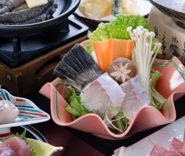 Assorted sashimi and vegetables arranged beside a tabletop hot pot at Kurhouse Shirahama Wakayama