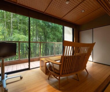 Wooden lounge chair and low table by glass doors opening to bamboo grove at Kuriya Yasohachi, Ishikawa