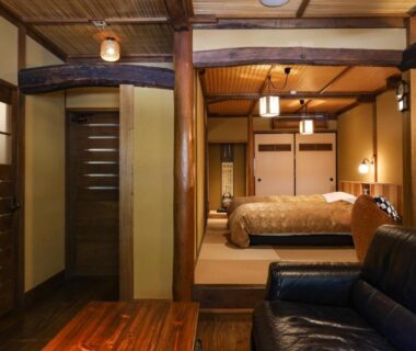 Tatami room interior with low table, leather sofa and shoji screens at Kurokawa Onsen Oyado Noshiyu in Kumamoto