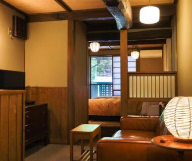 Interior of a ryokan room with tatami flooring, futon bed, wooden furnishings and paper lantern near shoji screen
