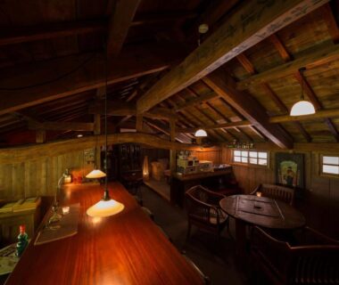 Warm wooden lounge with counter seating, exposed beams and pendant lamps at Kurokawa Onsen Oyado Noshiyu, Kumamoto