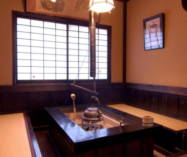 Traditional irori hearth in tatami room with shoji screens and wooden seating at Kurokawa Shinmeikan, Kumamoto
