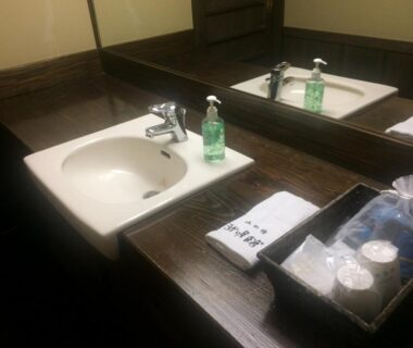 Bathroom vanity with sink, mirror, soap dispenser and amenities at Kurokawa Onsen Yama no Yado Shinmeikan Kumamoto Japan
