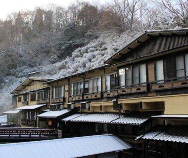 Snow-covered multi-storey ryokan exterior with wooden balconies at Kurokawa Onsen in Kumamoto, Kyushu