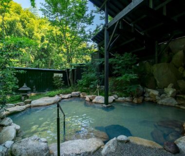 Outdoor stone onsen bath surrounded by lush greenery at Kurokawa-So in Kumamoto, Kyushu