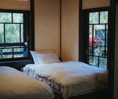 Two single beds with white linens and wooden windows overlooking garden, Kurokawa-So, Kumamoto, Kyūshū