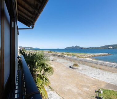 Balcony railing overlooking seawall, sandy shore and distant hills at Kurosakisou in Kyoto, Kansai