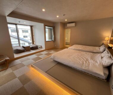 Modern tatami-style room with low beds, window seating and warm ambient lighting at Kusatsu Hotel Bekkan Wata no Yu