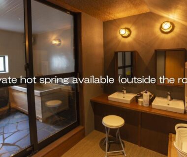 Sinks and vanity with glass partition revealing onsen bathing area at Kusatsu Onsen Eidaya, Gunma
