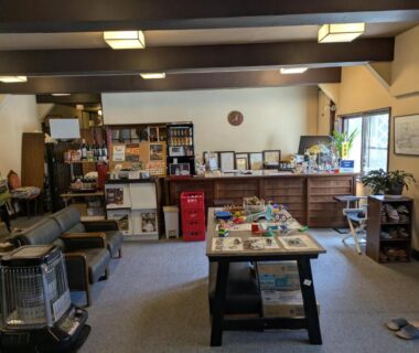 Cozy reception lounge with low table, chairs, bookshelves and portable heater at Kusatsu Onsen Eidaya, Gunma
