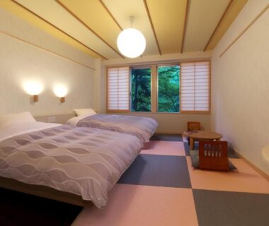 Japanese-style room with twin beds on tatami, shoji screens and greenery beyond the window at Kusatsu Skyland Hotel Gunma