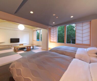 Spacious tatami room with twin beds, shoji screens and greenery outside at Kusatsu Skyland Hotel, Gunma