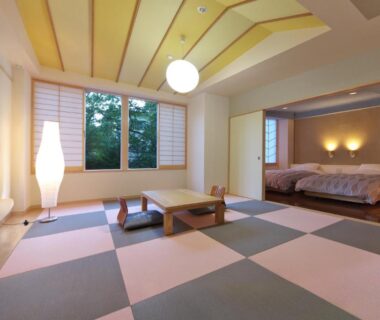 Modern tatami-style room with low table, shoji screens and adjacent beds at Kusatsu Skyland Hotel, Gunma