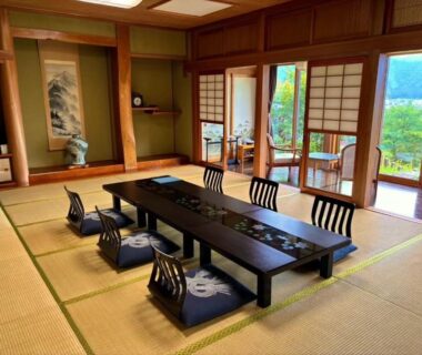Traditional tatami room with low table, zabuton cushions, shoji screens and veranda overlooking green hills