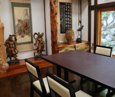 Dining table with chairs, carved wooden pillars, hanging scroll and shoji window at Kutsurogian in Niigata Chūbu Japan