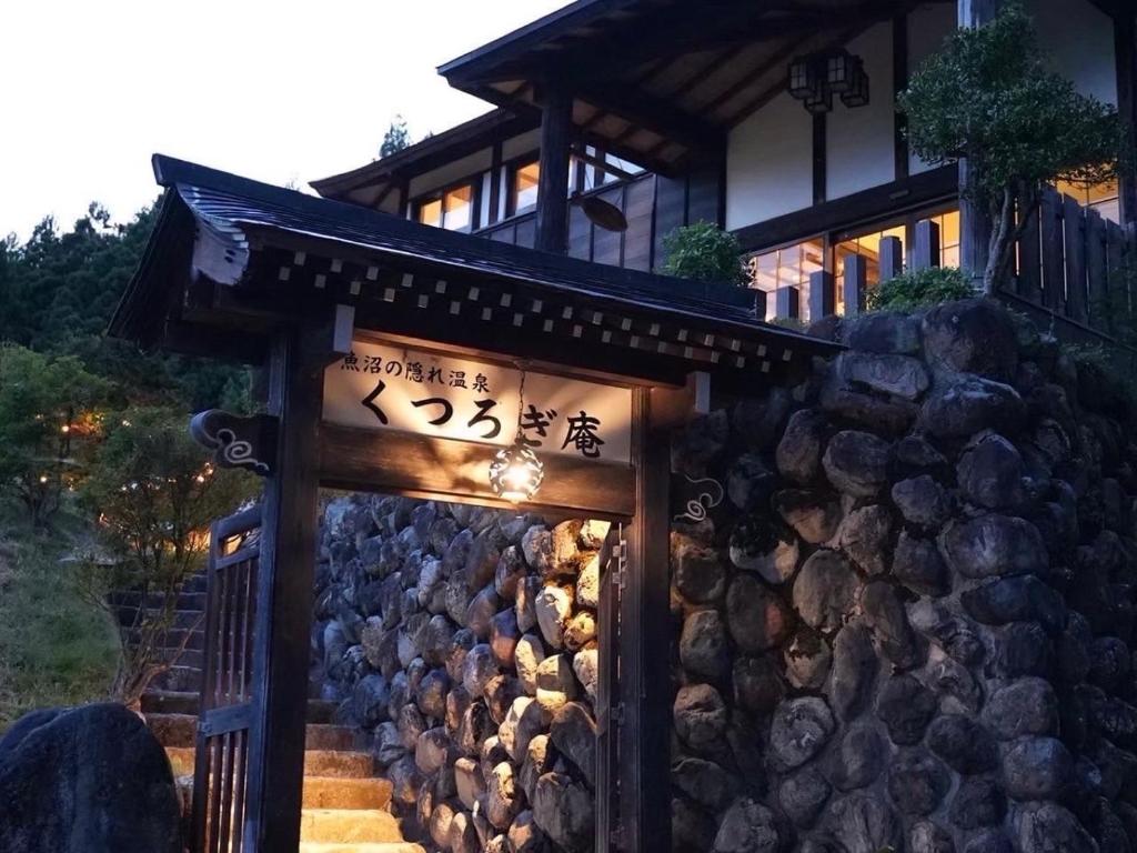 Stone entrance at Kutsurogian Niigata Lit wooden gate and stone wall entrance with steps leading to Kutsurogian ryokan in Niigata