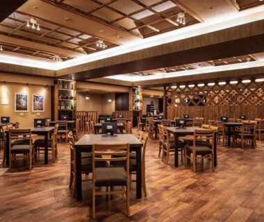 Warm wooden dining room with square tables and chairs, decorative lattice wall and ceiling beams at Kutsurogijuku Chiyotaki, Fukushima