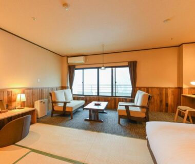 Tatami room with low table, armchairs, bed and wooden paneling at Kutsurogijuku Chiyotaki, Fukushima