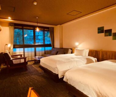 Two beds and seating area in Kutsurogijyuku Shintaki room, large window with view of greenery, Fukushima Tohoku
