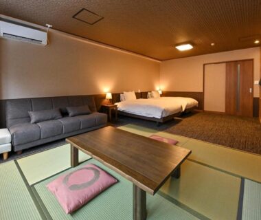 Tatami seating with low table, sofa and two beds in Kutsurogijyuku Shintaki room, Fukushima